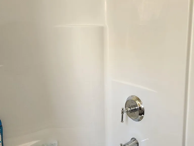 Clean tub/shower combo with smooth surround and chrome fixtures for easy daily use and quick cleanup.