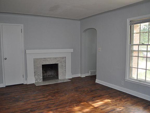 Sunny living room with renovated fireplace, arched entryway, and two coat closets