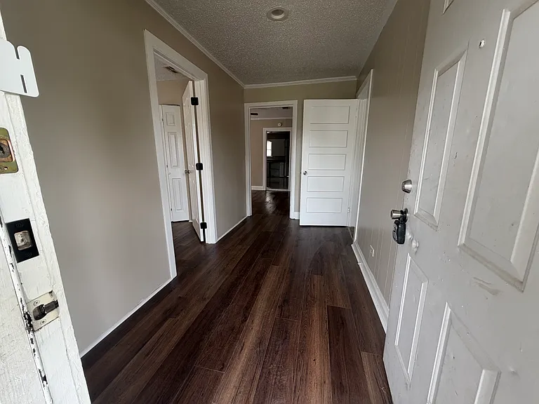 Entry way (hall) - 1st door (to left) - front bedroom - door opening (straight ahead) shows living room and the far room is the kitchen - door to the right - 2nd bedroom