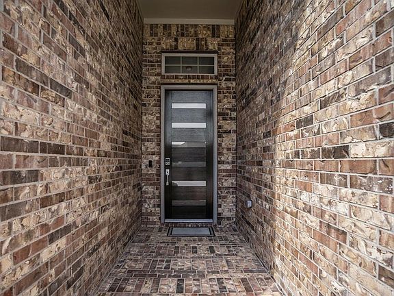 Front covered patio leading into the Patio Home through the beautifully upgraded wood and glass front door, which reflects light into the entry of the home.