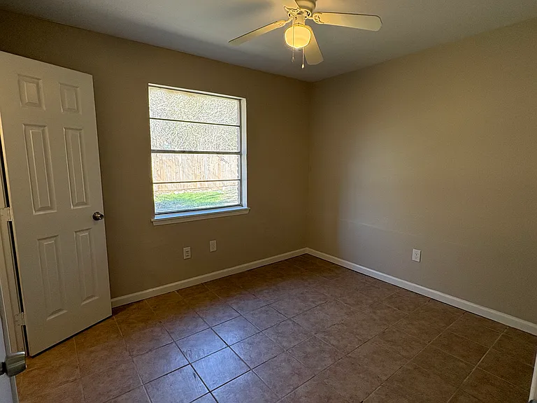 Second bedroom with closet and ceiling fan. Large window leading to back yard.