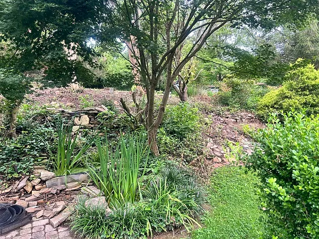 Gorgeous landing scaping including a water feature and quaint brick patio in the front yard