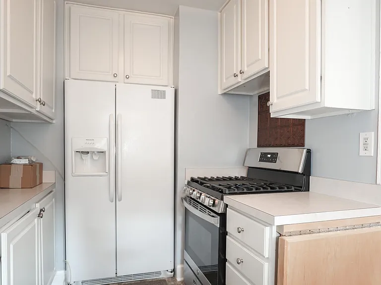 Alternate kitchen view with white cabinets and appliances.