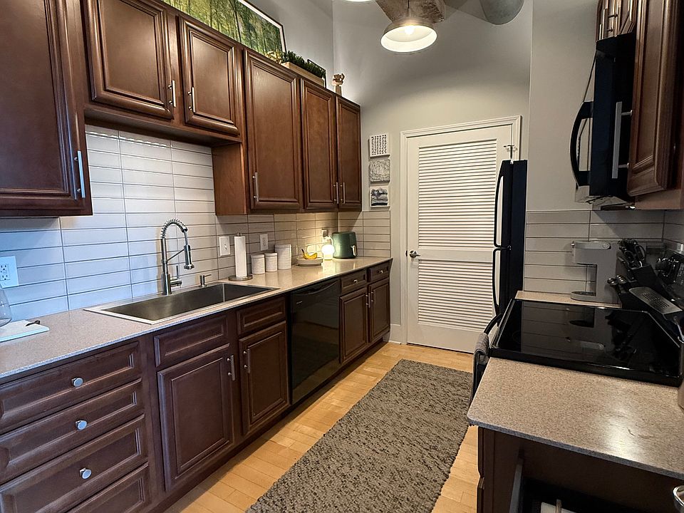 Kitchen features tiled backsplash and wifi-connected lighting underneath and above the cabinets for optimal lighting.