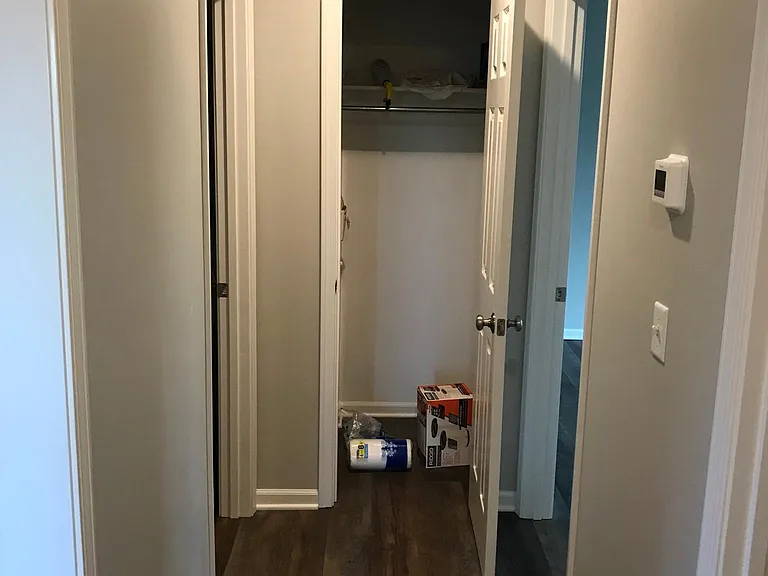 Hall with linen and hanging with Washer/Dryer supplied to left. Bedroom to right.