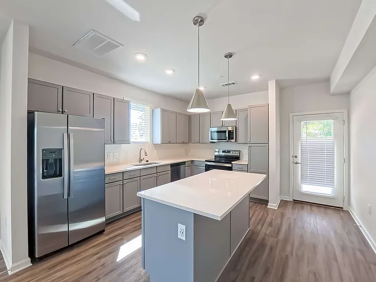 Modern kitchen with stainless steel appliances, sleek island, and elegant pendant lighting.
