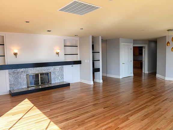 Sunny living room hardwood floors, with luxurious marbeled gas fireplace and built-ins.