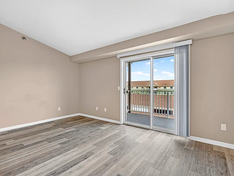 Elevate your lifestyle at Minot Place Apartments. This spacious living area features stunning wood-style flooring and invites natural light through sliding glass doors. Enjoy a fresh startschedule your tour today to see your new home!