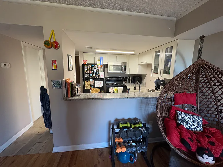 View of kitchen from the living room/dining room space. White door on the left is to bathroom.