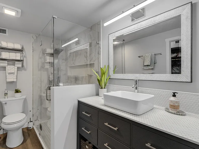 Redesigned primary bathroom, with tiled counters, glass-enclosed shower and elevated shower hardware