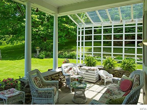 Terrace with trellis soon to be in full bloom, perennial flower beds along stone walls