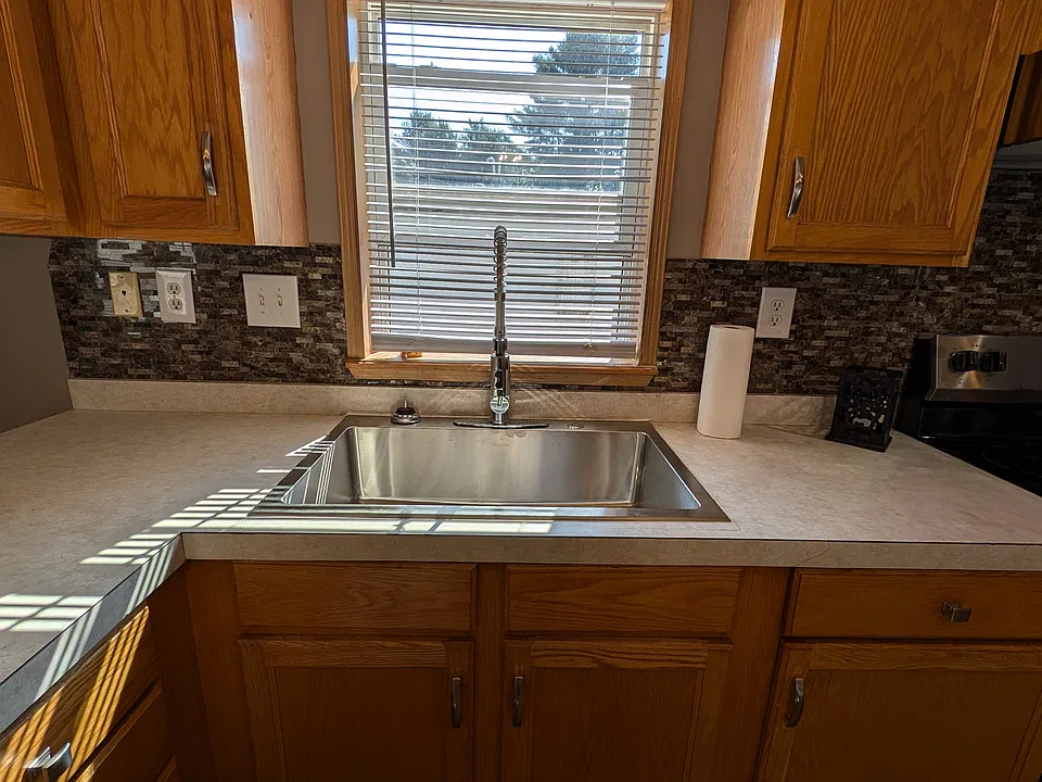 Large bowl sink with commercial faucet and window above sink