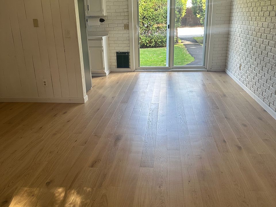 Living room facing north with sliding glass doors. Path leads out to driveway and carport. Kitchen on left