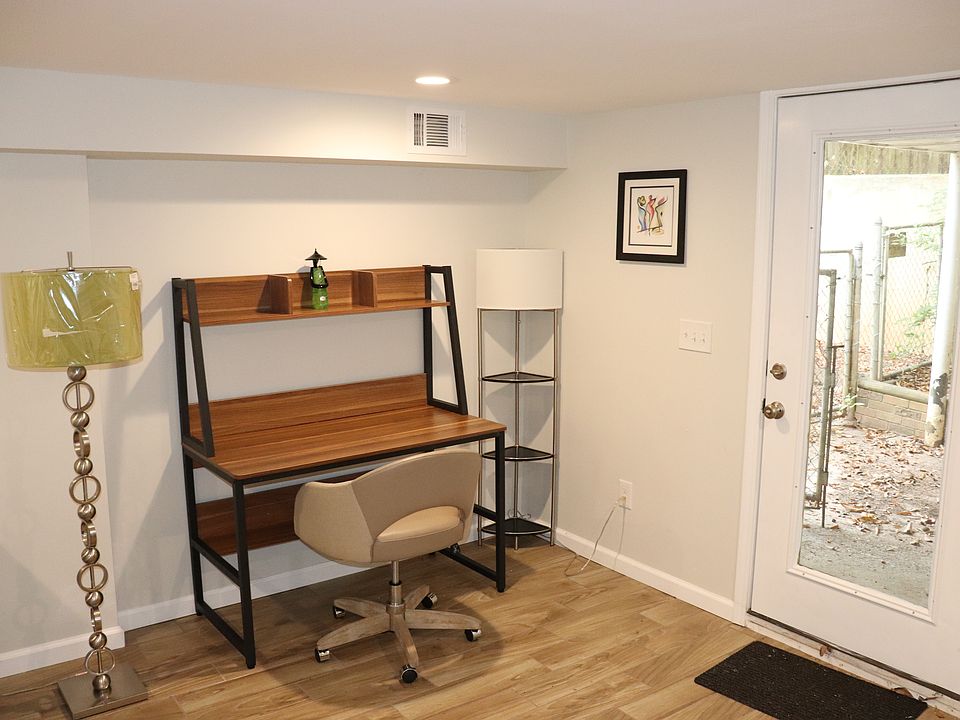 The work area has a gread desk, lighting, and comfy elegant office chair.