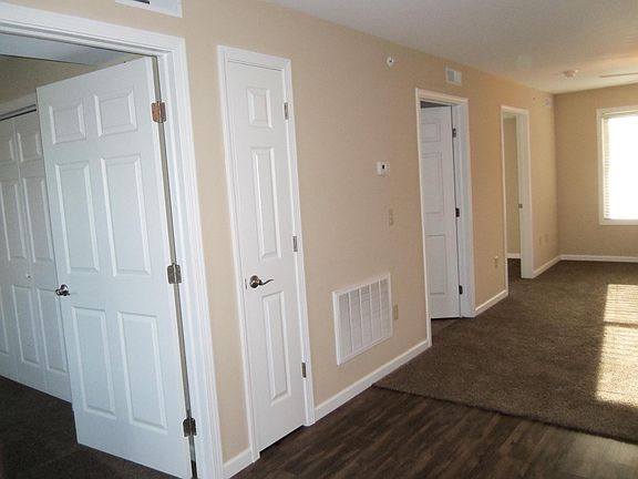 Looking at two bedrooms and bathroom doors and living room.