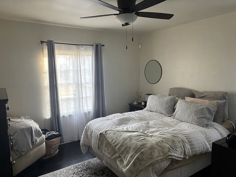 Large secondary bedroom filled with natural light, featuring two oversized windows, a ceiling fan, and a roomy walk-in closet.