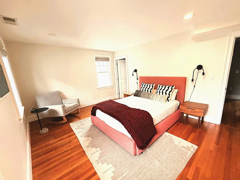 Spacious primary bedroom with hardwood floors, room for sitting area, custom linen Roman shades and excellent natural light