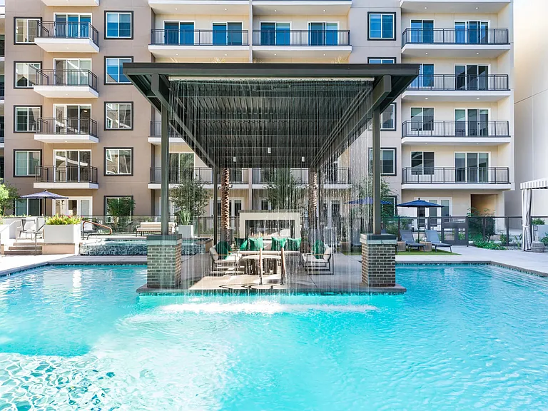 Our resort-inspired pool features a dramatic rain curtain and shaded seating area, perfect for relaxing or socializing in style.