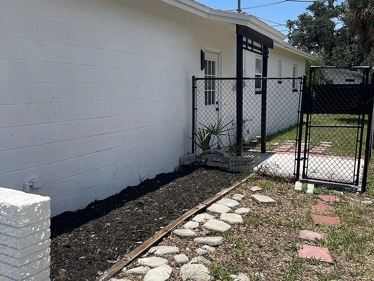 right side of the house fenced with gate and door that leads to the garage too