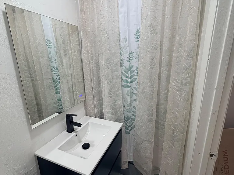 Updated bathroom with a sleek vanity, framed mirror, and shower/tub combo with curtain for everyday convenience.