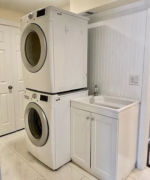 Separate laundry room tile flooring and front loading washer and dryer.