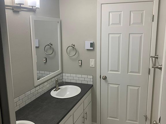 Bathroom with dual sinks and separate toilet/bath area.