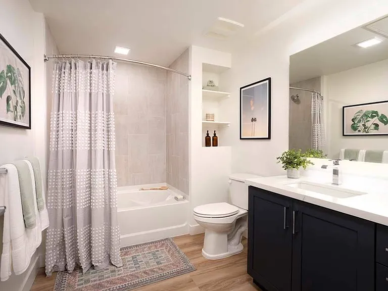 Stylish bathrooms feature large frameless mirrors, quartz countertops, modern cabinetry, and soaking tub with custom tile surround