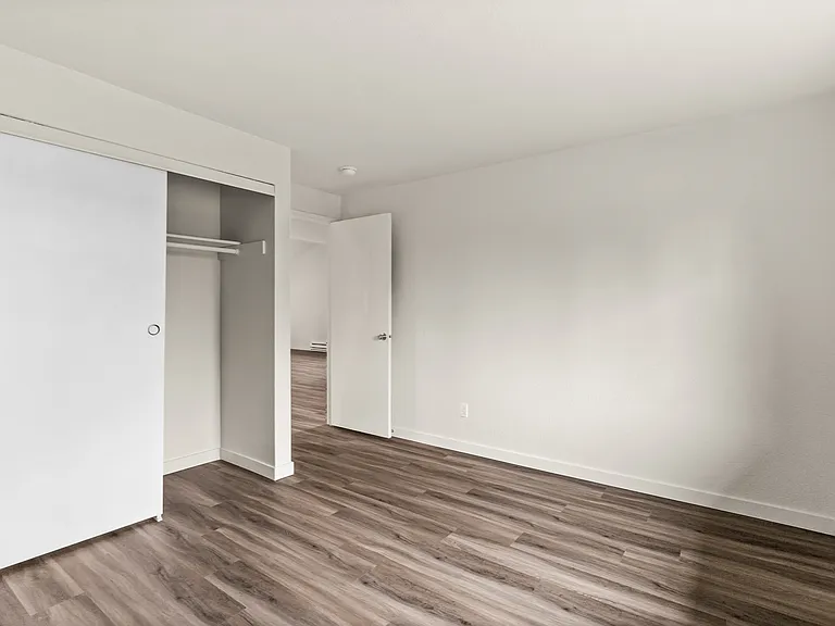 Spacious bedroom with elegant wood flooring and a large sliding closet door. Spacious bedroom with elegant wood flooring and a large sliding closet door.