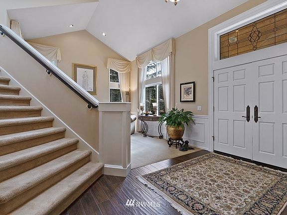 2 story foyer with wainscoting and Fine Arts chandelier and sconce lighting. 