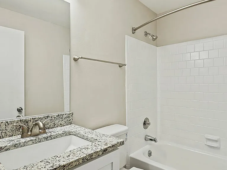 Step into luxury with this modern bathroom featuring a granite-topped vanity and stylish finishes.