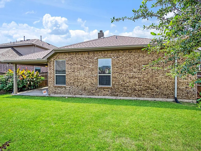 Expansive green lawn bordering a brick exterior with two prominent windows
