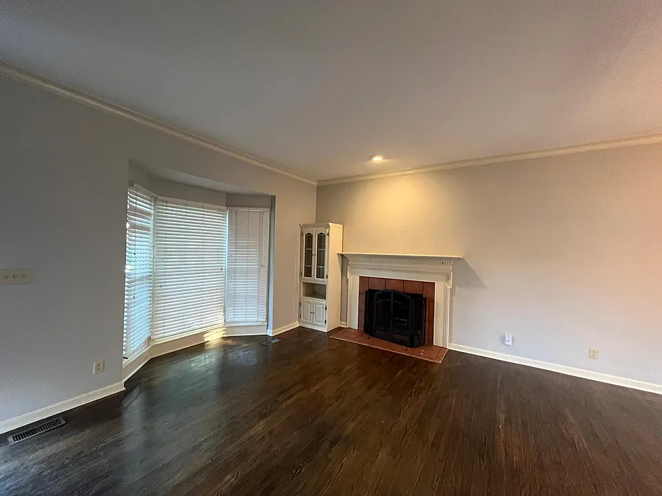 Living room displaying fireplace build end cabinet and bay window