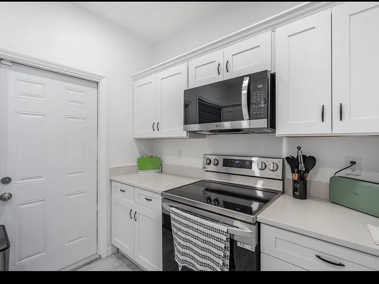 Efficient kitchen with ample white cabinetry, generous prep space, and stainless-steel range with over-the-range microwave.