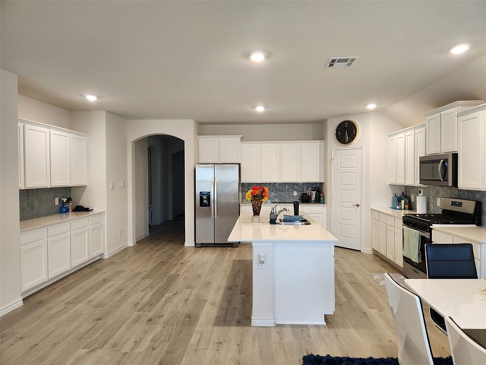 Open-concept kitchen featuring white cabinetry, light-toned wood-finish flooring, a central island with a sink, stainless steel appliances, and recessed lighting