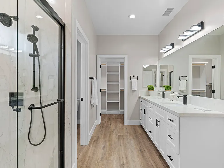 Primary en-suite bathroom with walk-in shower, double sinks and two walk-in closets