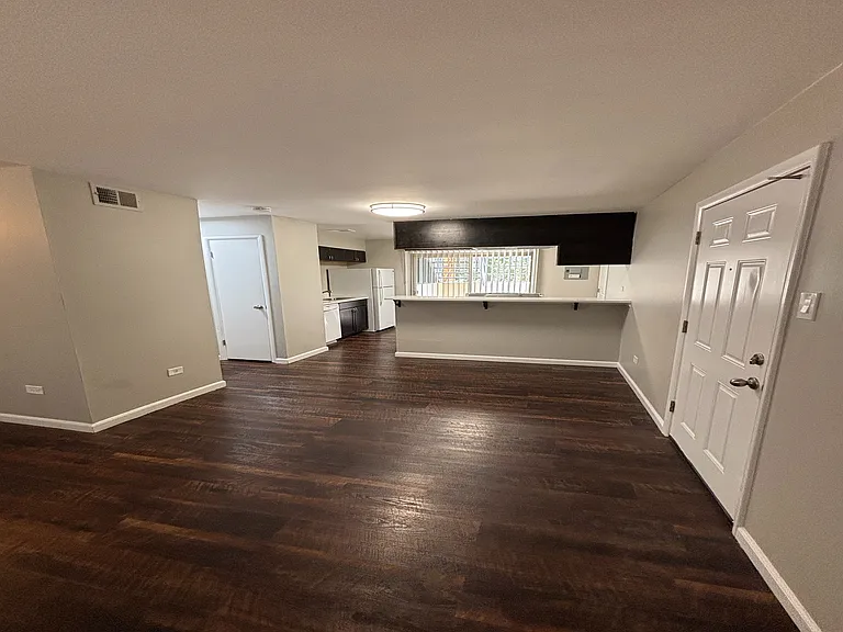 Inviting open-concept living area with rich wooden flooring and a cozy kitchen nook.
