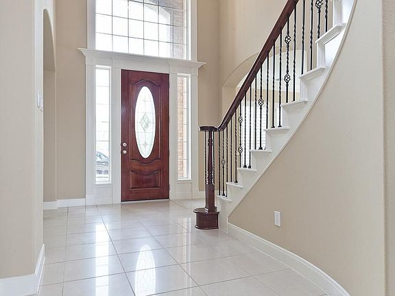 Another view of the entry which features a leaded glass front door and upgraded chandelier. There is also a closet underneath the stairwell.