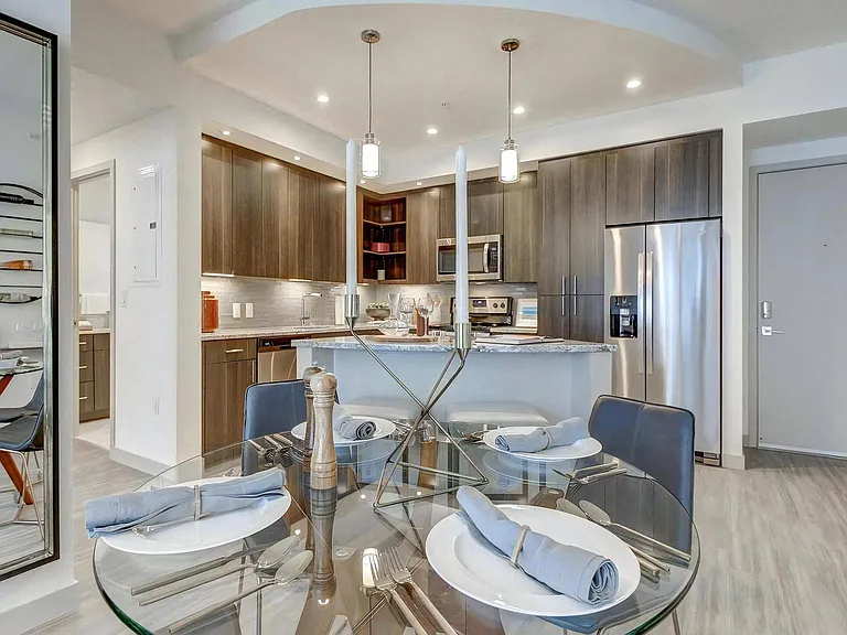 Dining Area With Round Glass Table and Open View Into Stainless Steel Kitchen