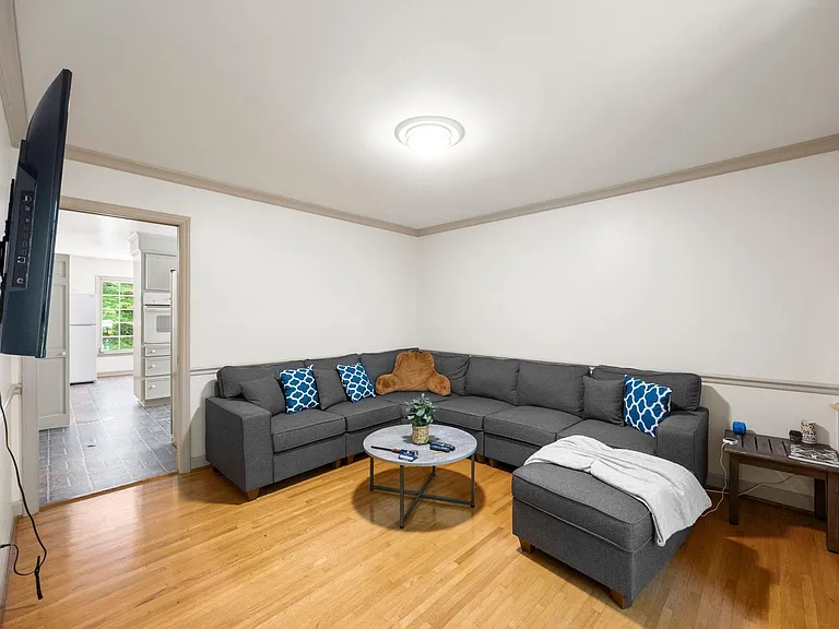 Spacious living room with a sectional layout, hardwood floors, and open flow to the adjacent kitchen area.