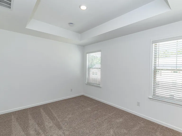 Cozy third bedroom with plush carpet and natural light from ample windows.