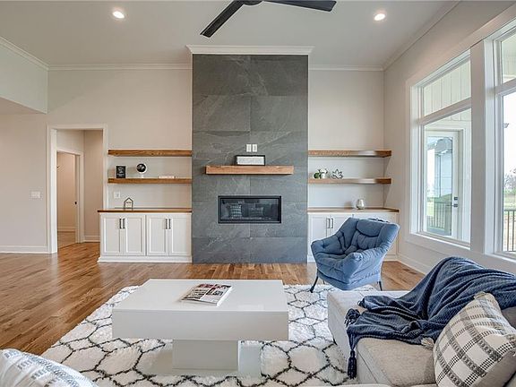 Living room with wood floors, a gas, tiled fireplace, and large windows