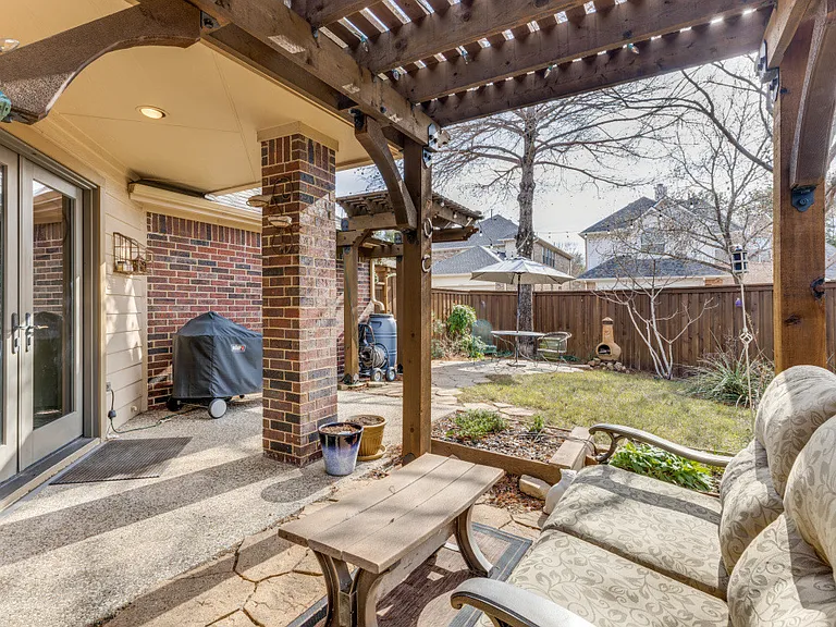 View of patio featuring a pergola and area for grilling. Rain collection barrel and carefully designed landscape make this a haven for escape.