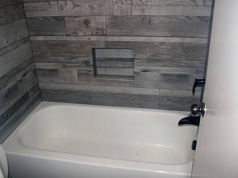 Fully remodeled master bathroom tub and shower with wall-to-wall imported tile with wall insert and bronze fixtures.