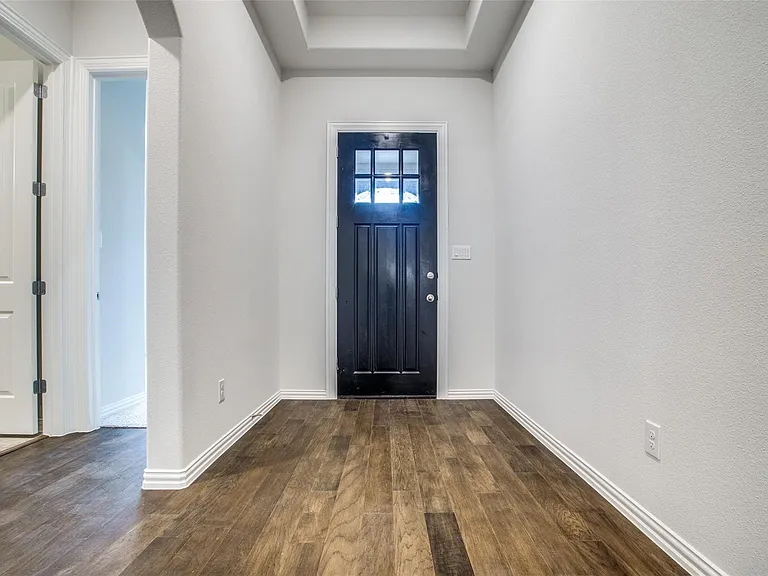 Entryway featuring wood-finish flooring, a coffered ceiling, and a dark paneled door with glass inserts