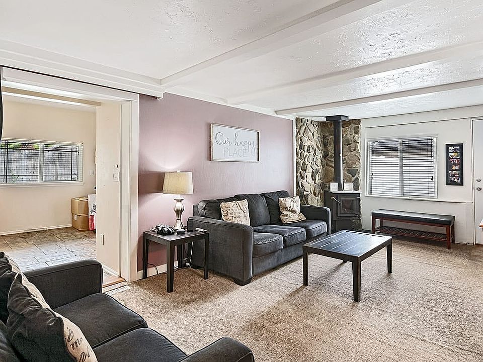 Living room with fireplace. Office area off to the left. This photo shows the room with a rug, which has been removed and hardwood floors are underneath.