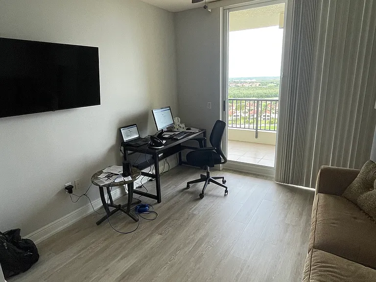 Third bedroom has desk and office chair with a large TV, ceiling fan, and walk in closet