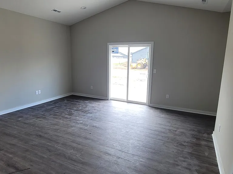 Open living room with natural light through sliding glass door leading to patio area