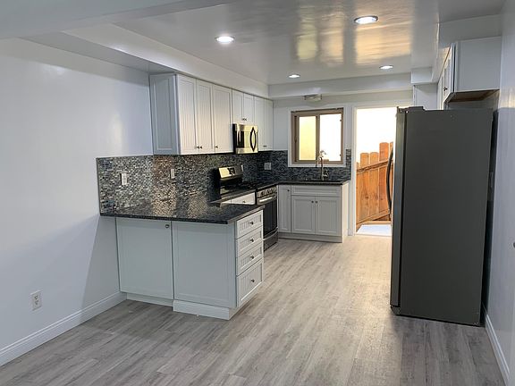 Gorgeous gourmet kitchen with beautiful blue granite breakfast bar and counters with custom ocean glass backsplash and soft close cabinetry plus top stainless appliances.
