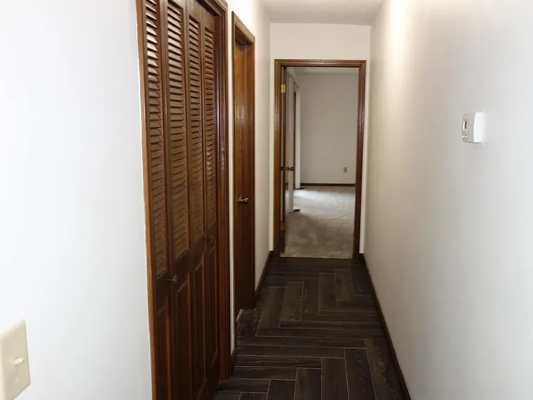 Hallway leading to master bedroom straight ahead. Linen closet with bifold doors on left and 2nd bedroom door on left.