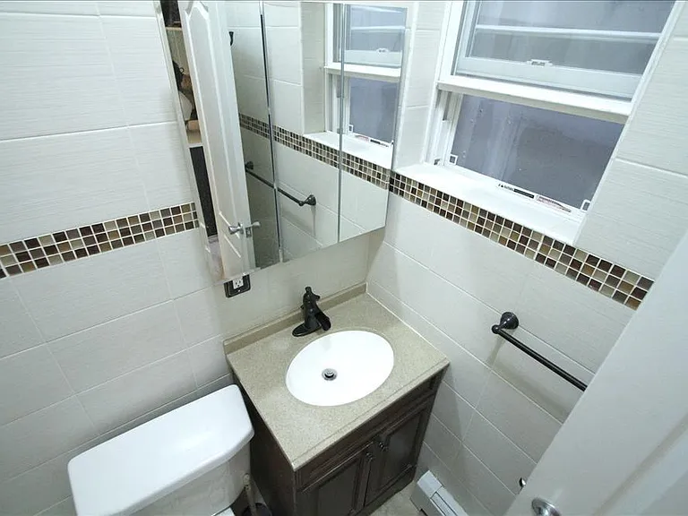 Full bath with shower/tub combo, tile surround, and convenient fixtures for everyday use + window for ventilation & light.